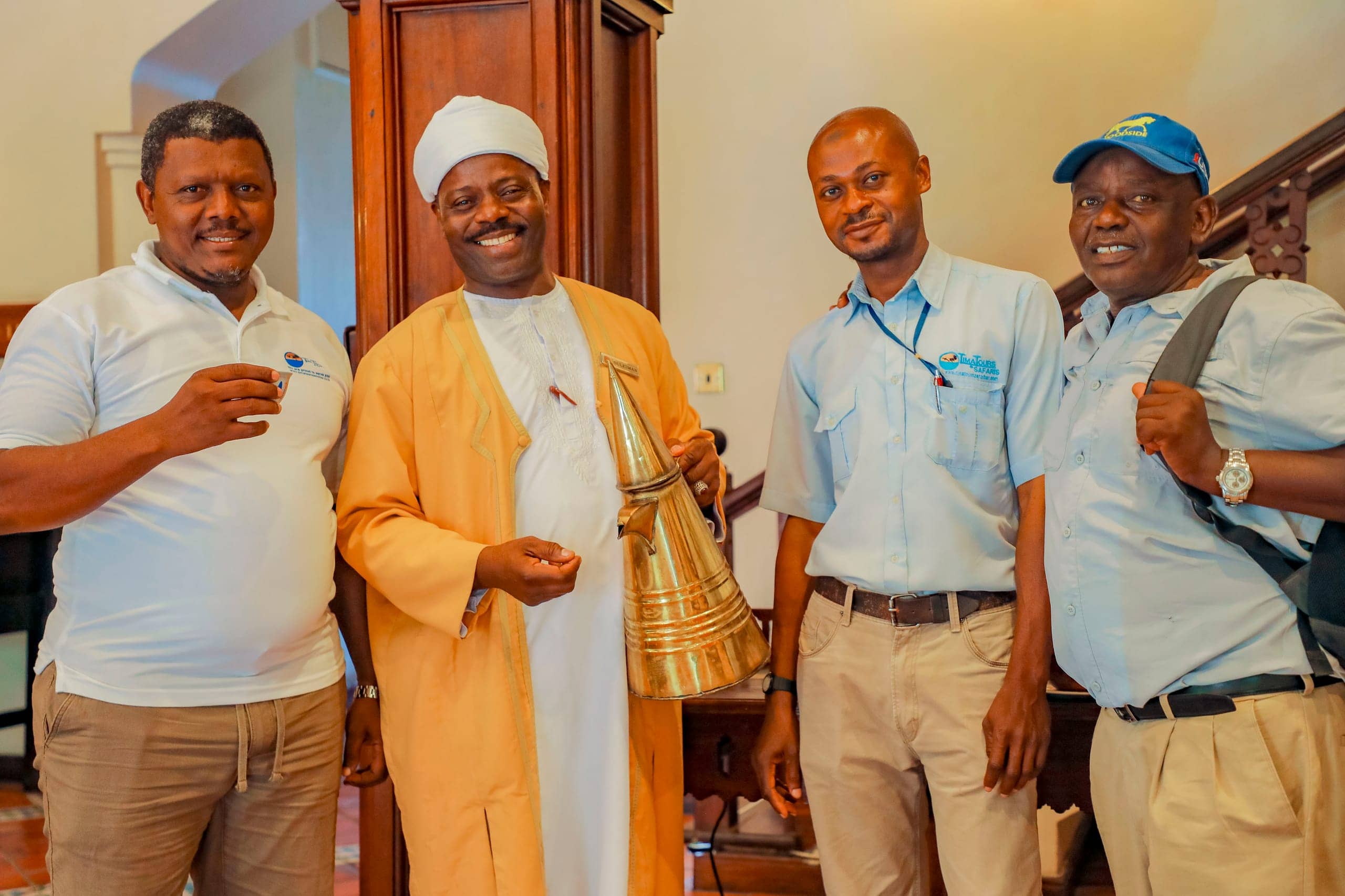 Salum and two Tima Tours guides with a traditional coffee seller holding a brass coffee pot in a Stone Town hotel