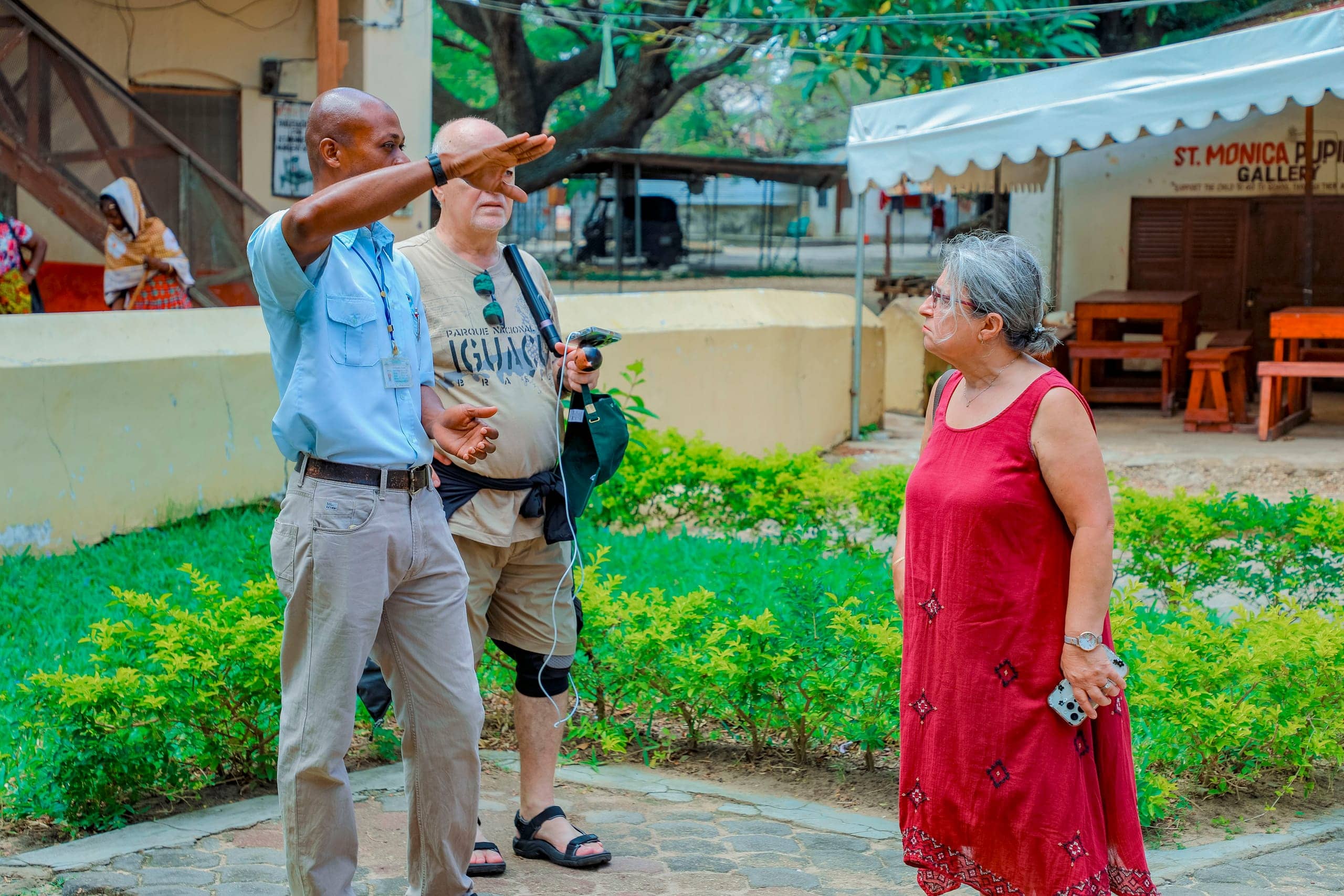 A Tima Tours guide pointing out a building to two guests in a Stone Town courtyard