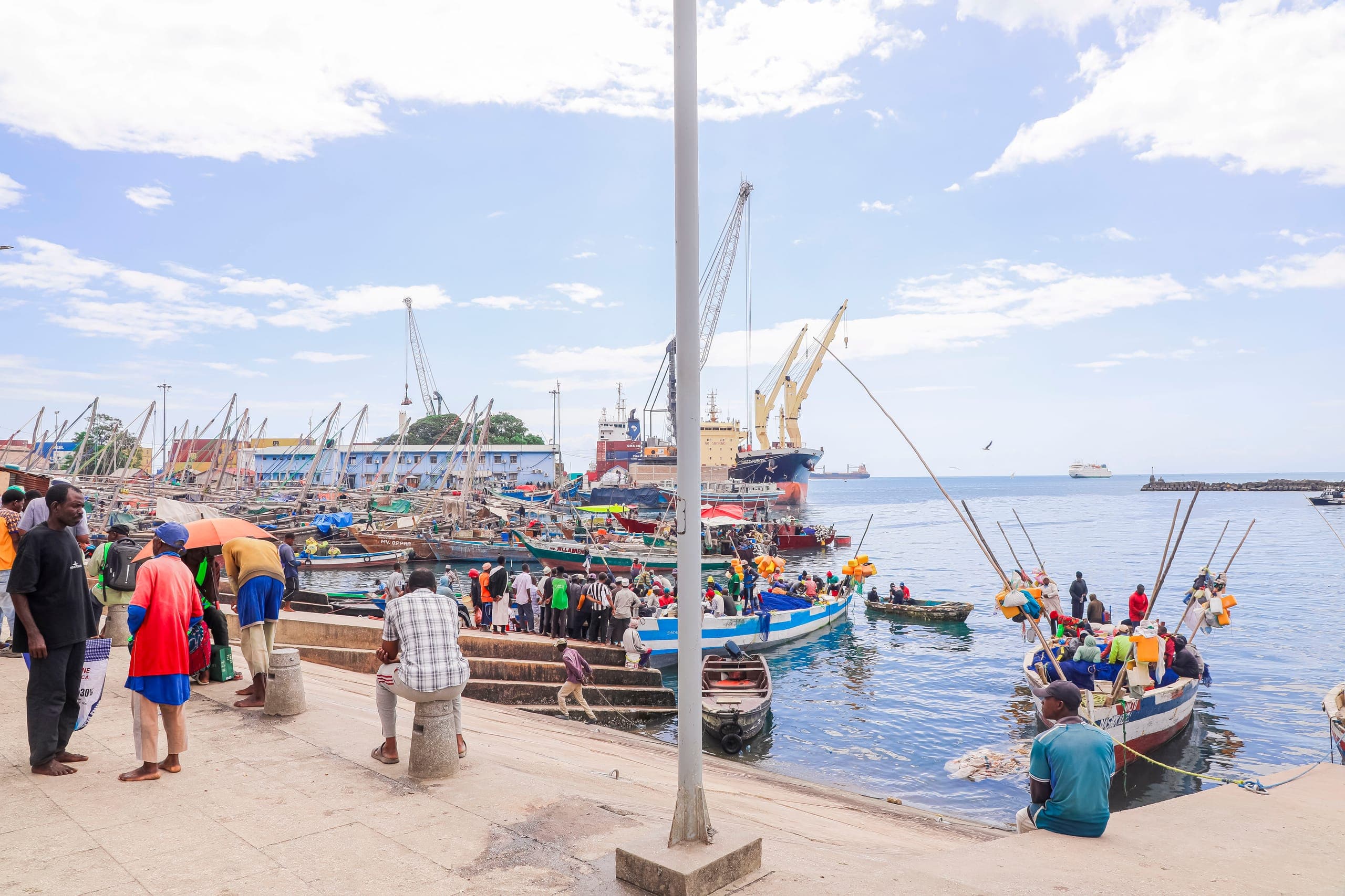 Fishermen and wooden boats at the Stone Town fish market harbour under a blue sky