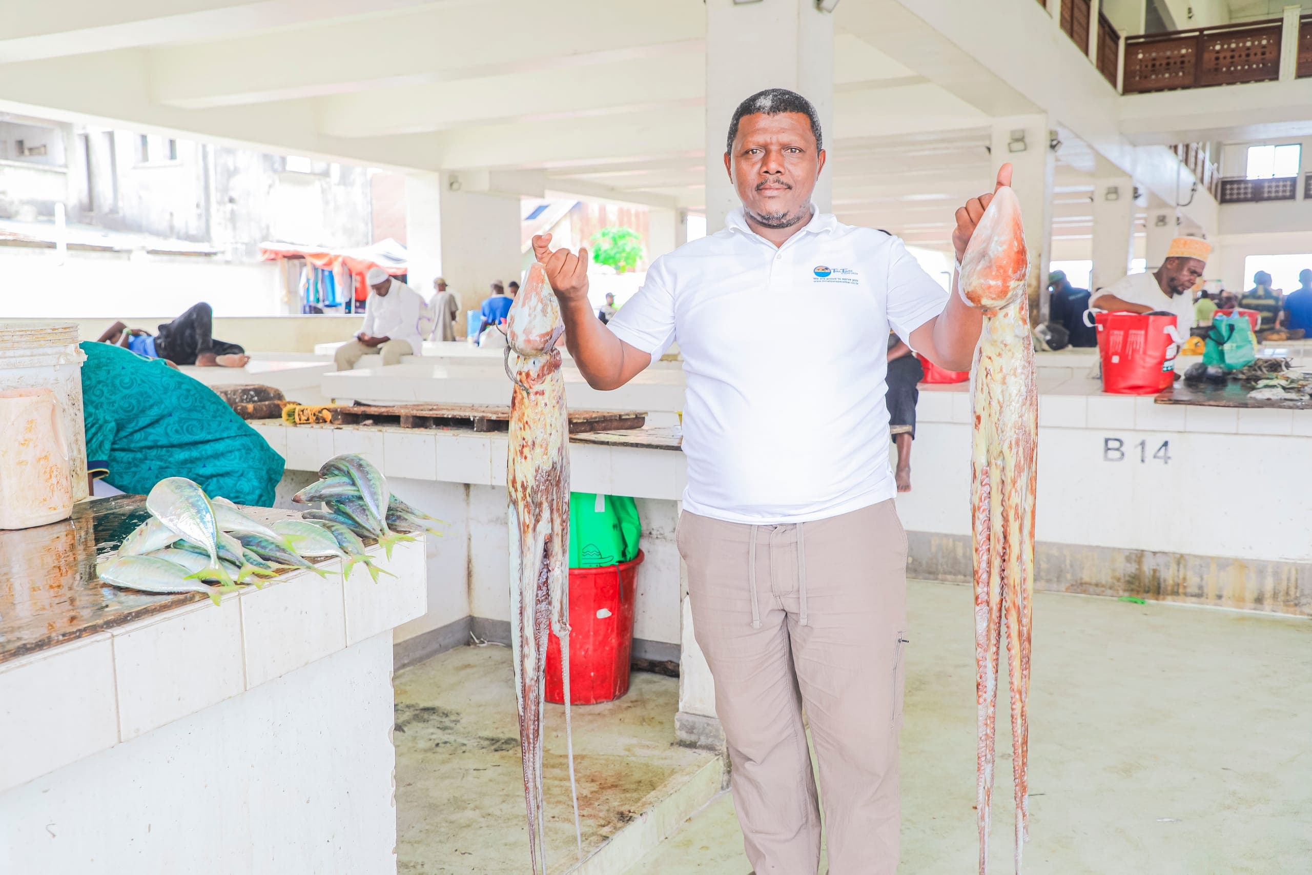 Salum, founder of Tima Tours, holding up two large squid at the Stone Town fish market