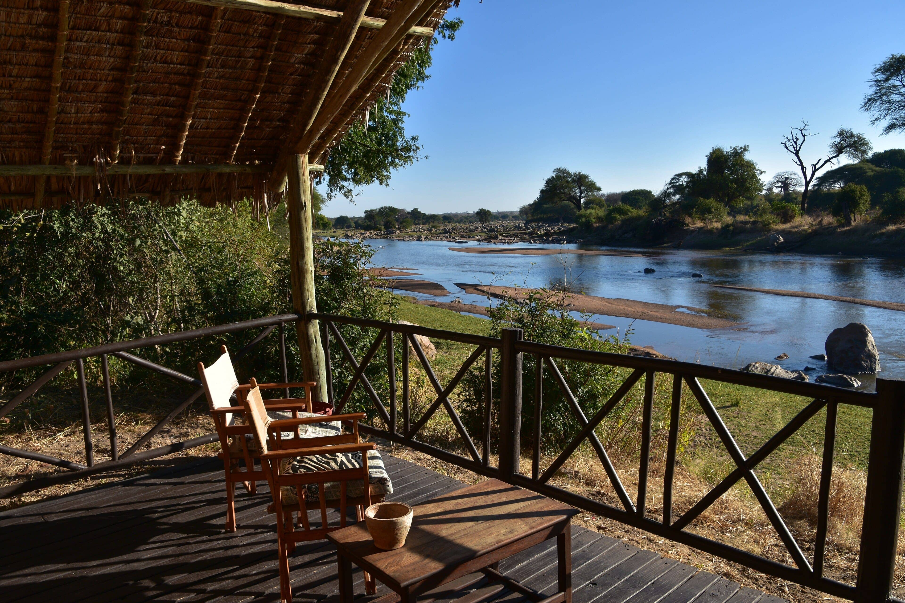 A veranda of Ruaha River Lodge over the Great Ruaha river, with chairs facing the water