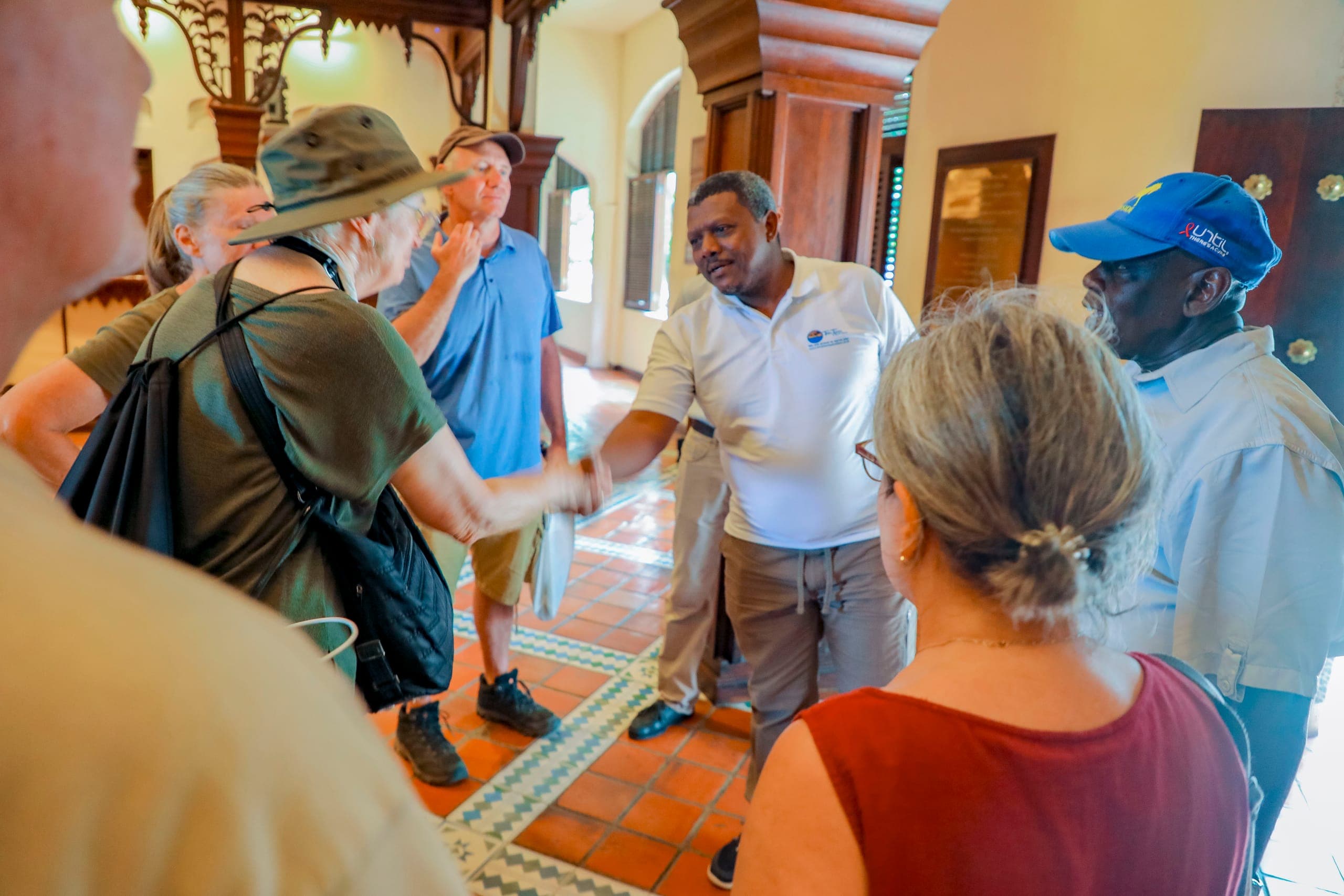 Salum, founder of Tima Tours, shaking hands with a guest in the tiled hall of a Stone Town hotel